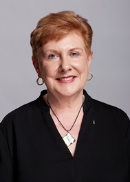 image of older woman with short auburn hair, gold hoop earrings and black shirt